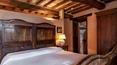 Toscana Immobiliare - The bedroom has an antique wooden bedstead, bedside tables, lamps and a large wooden wardrobe.