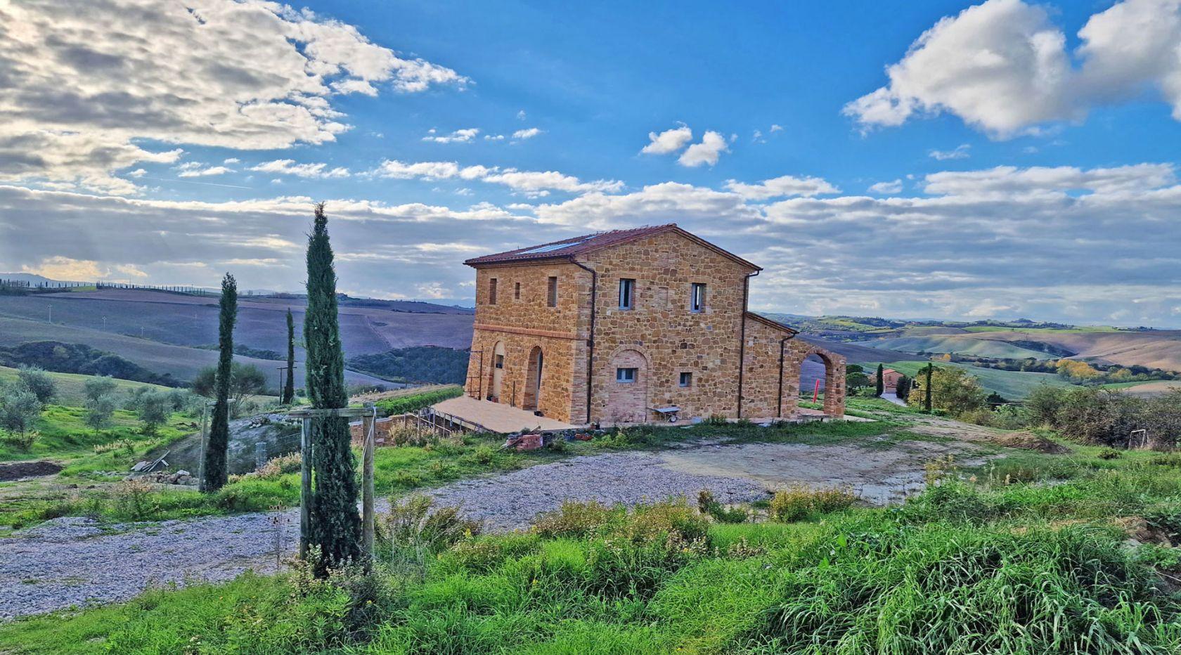 Toscana Immobiliare - Montalcino, in a dominant position on the hillside, surrounded by the verdant Tuscan countryside and the characteristic Crete Senesi, renowned for the beauty of its landscapes, this charming farmhouse is for sale.